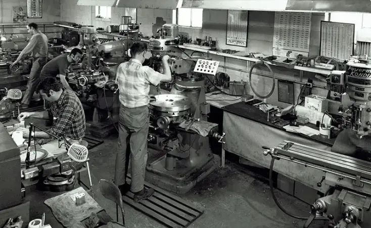 A man working in an industrial setting with many machines.